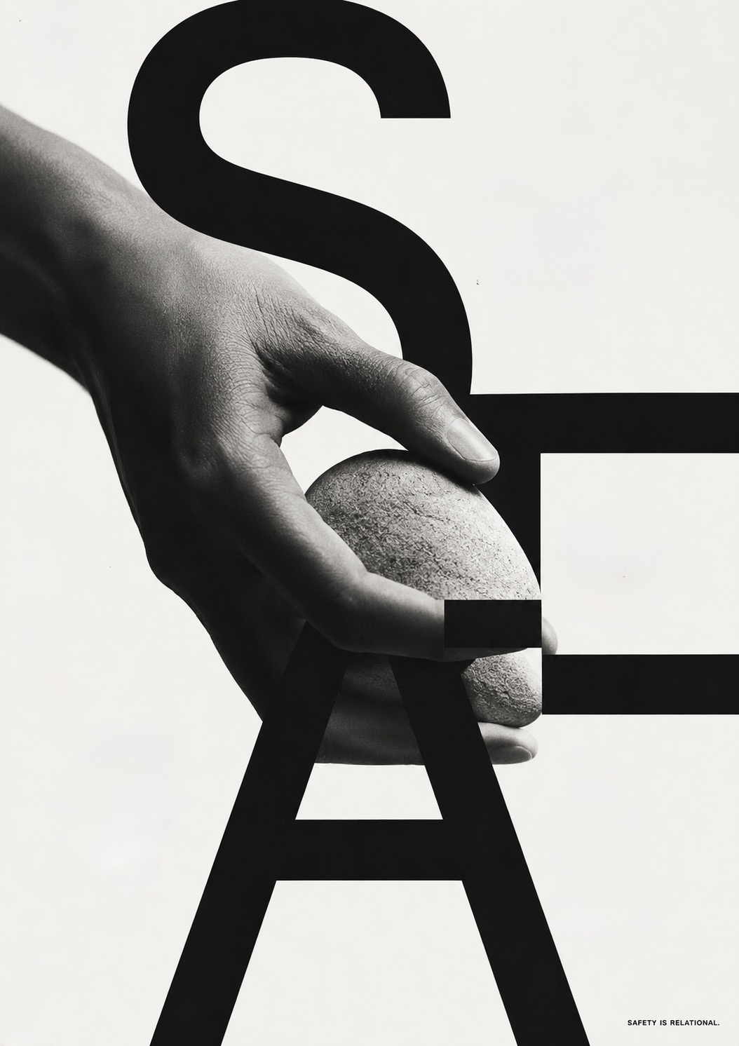 A hand cupping a smooth stone inside the monumental letters of the word SAFE, with the line ‘safety is relational’ set small at the foot.