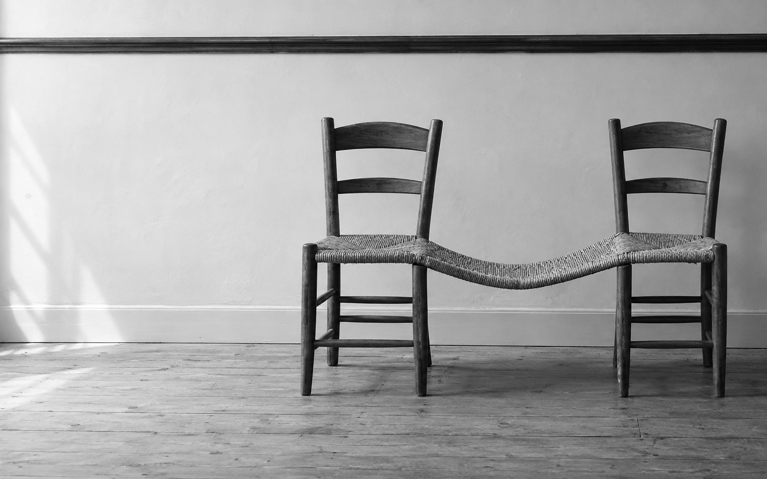 Two empty chairs share one continuous woven seat.