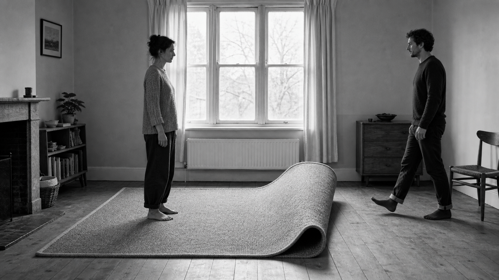 A man crosses a room towards a woman standing still, and the rug between them curls up into a wave that has not yet reached her.
