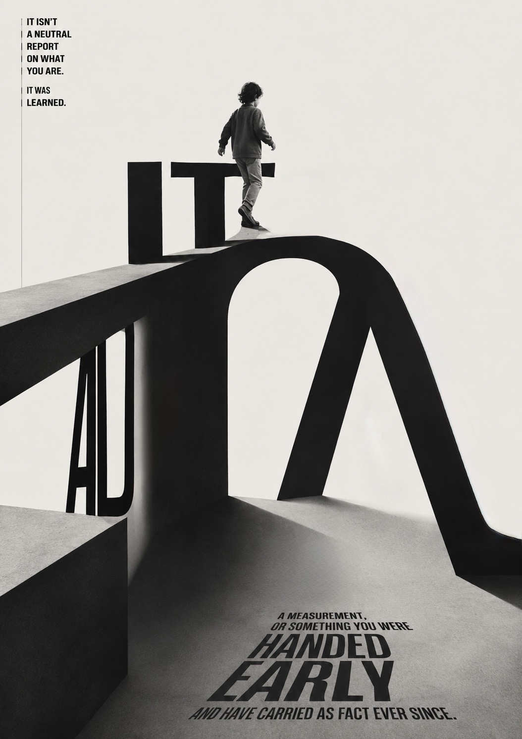 A child walks along the top of the monumental word ‘IT’ set into an impossible looping structure, with ‘it isn’t a neutral report on what you are — it was learned’ above and ‘a measurement, or something you were HANDED EARLY and have carried as fact ever since’ across the floor.