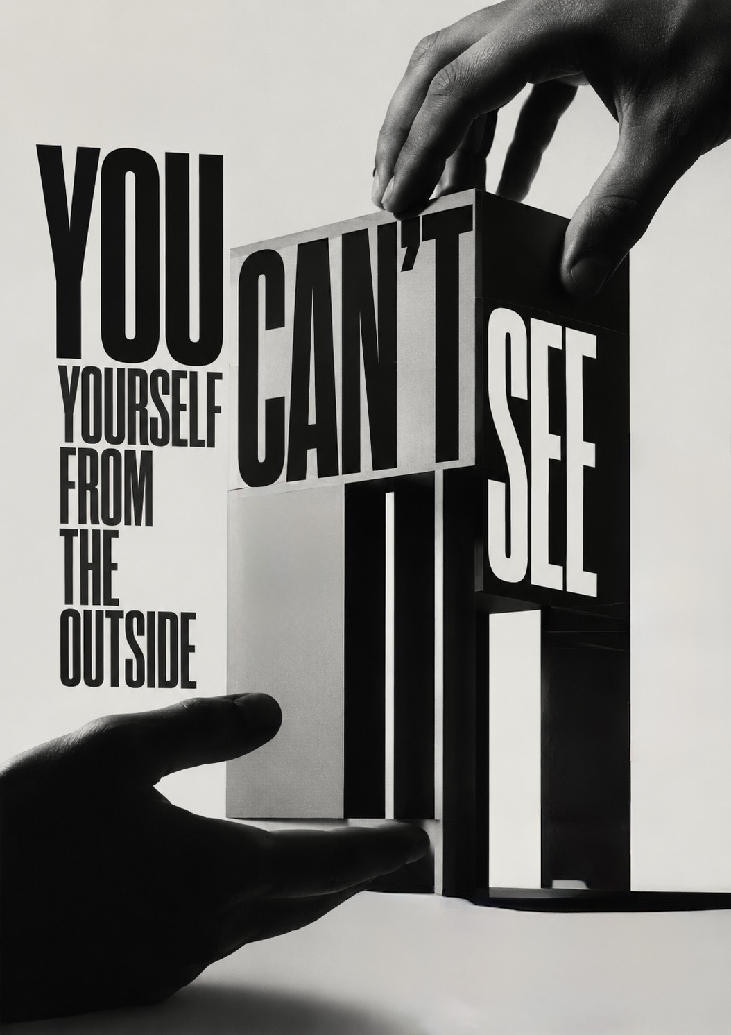 Two hands turn a monumental sculptural block spelling ‘YOU CAN’T SEE’, beside the words ‘you can’t see yourself from the outside’ — the picture that can only be corrected by being seen clearly by someone else.