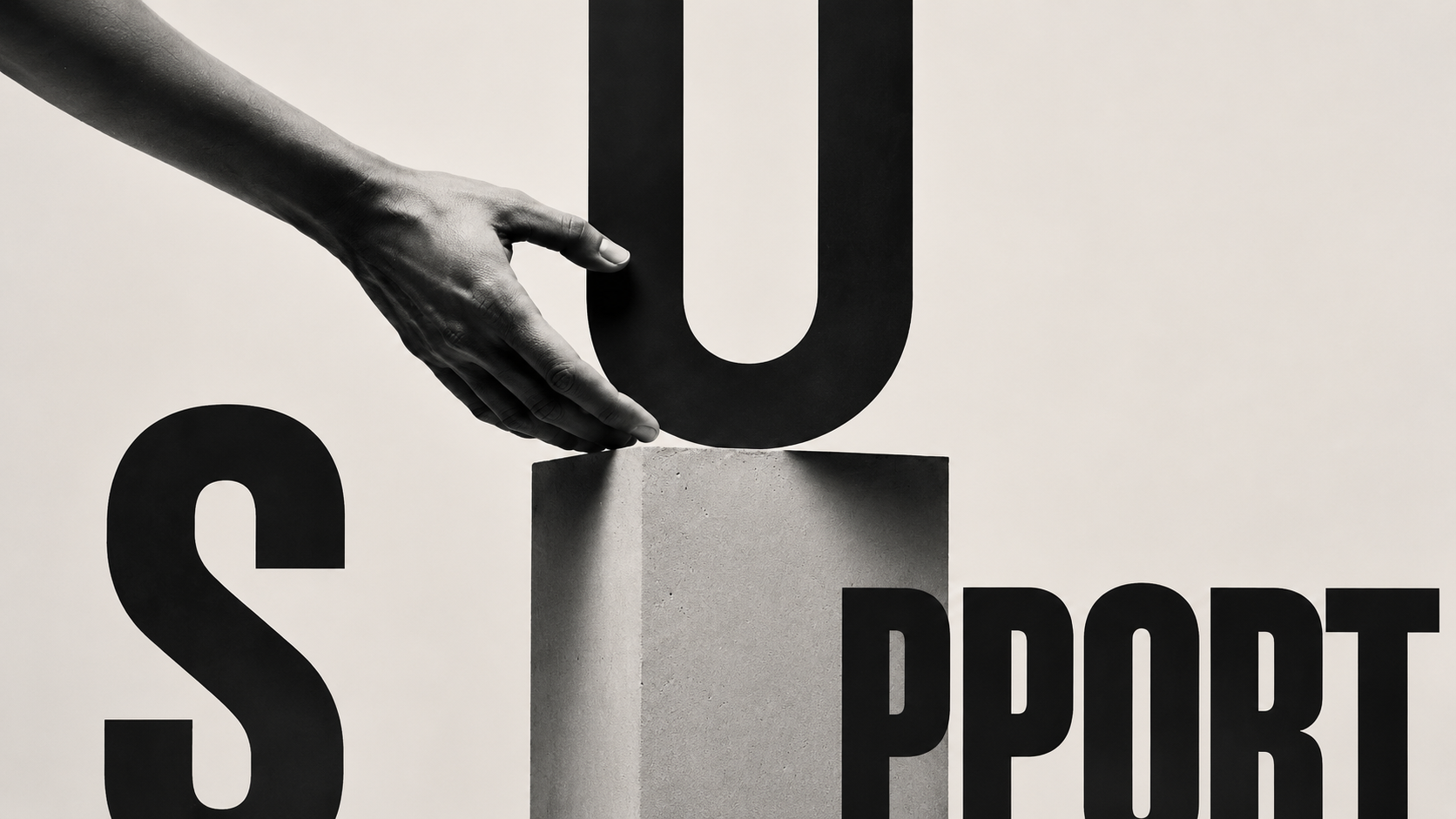 SUPPORT, a hand resting a giant letter U on a concrete plinth.