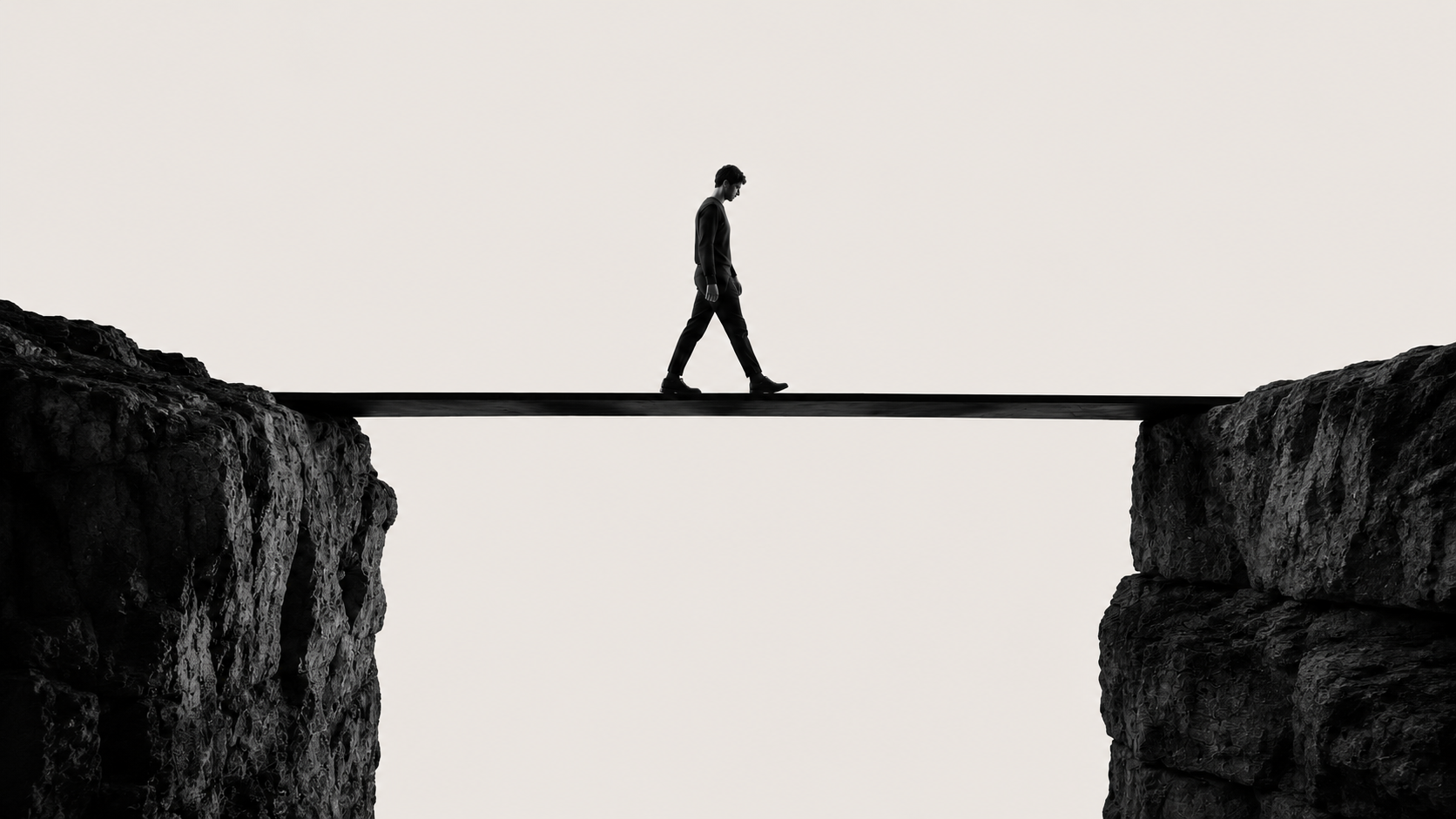 A figure walking a narrow plank bridge across a gap between two cliffs.